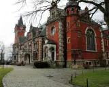 Pławniowice atrakcje: okazały pałac z czerwoną cegłą, wieżą zegarową i brukowanym dziedzińcem.