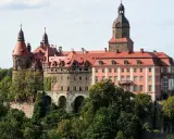 Zamek Książ z czerwonymi dachami i wieżami, otoczony zielenią. Sprawdź zamek książ cennik zwiedzania.