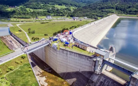 Impreza nad Jeziorem Mucharskim. Ludzie spacerują po zaporze, podziwiając widoki i korzystając z atrakcji.
