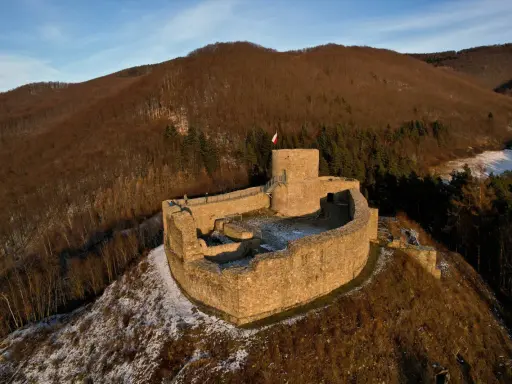 Ruiny zamku w Rytrze, z polską flagą na wieży. Warto sprawdzić zamek w Rytrze cennik przed wizytą.