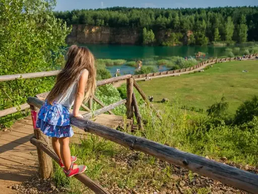 Dziewczynka na drewnianej kładce podziwia Park Gródek Jaworzno. Warto sprawdzić cenę wstępu, by cieszyć się tym widokiem!