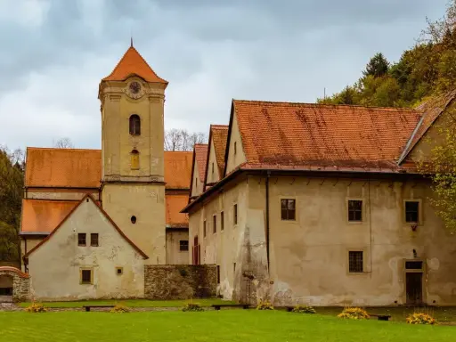 Czerwony Klasztor z wieżą zegarową i pomarańczowymi dachami. Sprawdź cennik zwiedzania tego zabytku.